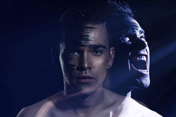 Handsome caucasian guy with agressive shadow face of himself - 写真・画像