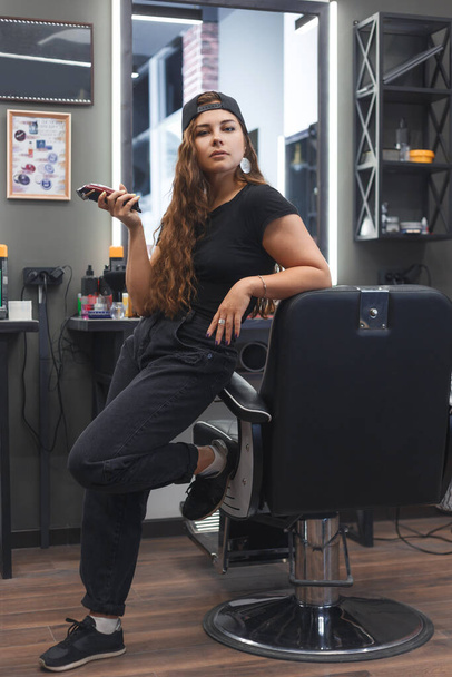 młoda kaukaska fryzjer kobieta trzyma a obcinacz i stojąc w miejscu pracy - Zdjęcie, obraz