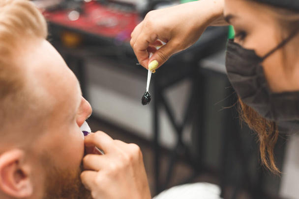 Removing hair from the nose with wax in barbershop, male beauty and care concept - 写真・画像
