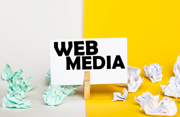 papel blanco con texto Web Media en un tendedero sobre fondos amarillos y blancos con fajos de papel de diferentes colores - Foto, Imagen