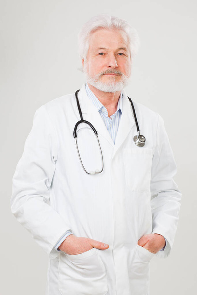 Handsome elderly doctor in uniform isolated over light background - Foto, afbeelding