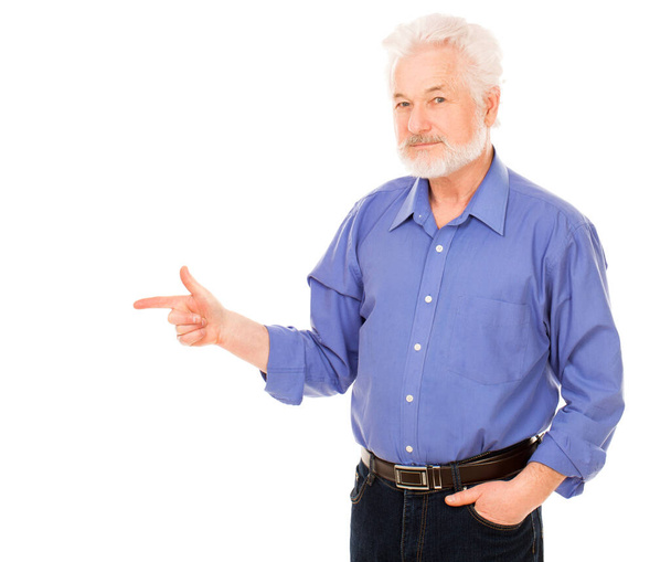 Schöner älterer Mann mit grauem Bart zeigt auf etwas Vereinzeltem vor weißem Hintergrund - Foto, Bild