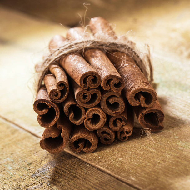 Stack of cinnamon wrapped with a rope over a wooden surface - Фото, зображення