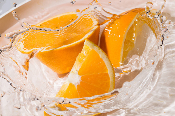 Slices of an orange splash into the water - Photo, Image