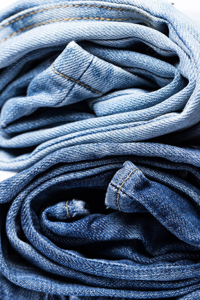 Uma pilha de vários pares de jeans sobre um fundo branco - Foto, Imagem