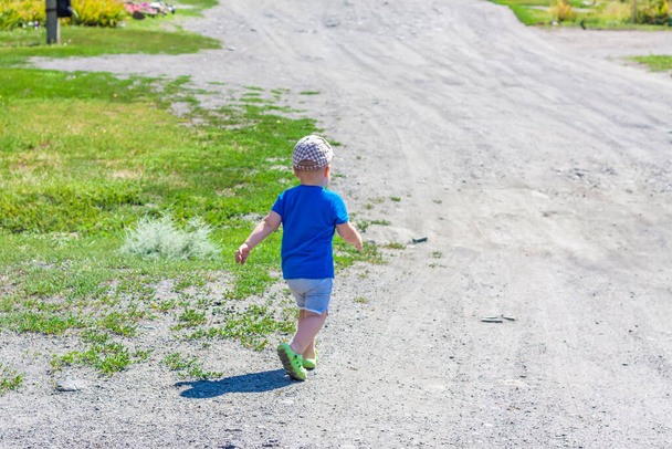 A small boy is walking along a rural street. Walking down the street on a summer day. - Фото, зображення