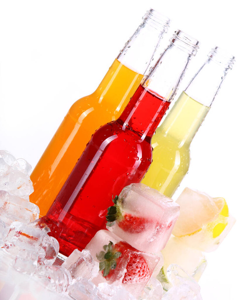 Flessen met kleurrijke cocktail en ijs op witte achtergrond - Foto, afbeelding