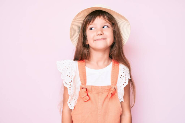 Little caucasian kid girl with long hair wearing spring hat looking to side, relax profile pose with natural face and confident smile.  - Foto, immagini