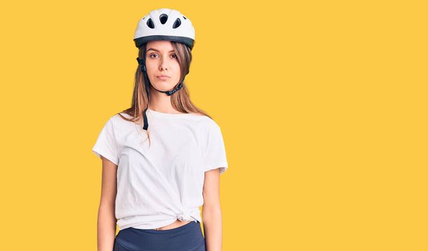 Menina bonita nova usando capacete de bicicleta com expressão séria no rosto. simples e natural olhando para a câmera.  - Foto, Imagem