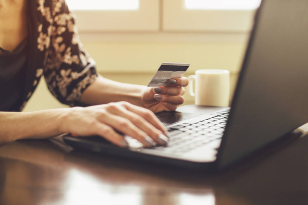 Fiatal nő kezében hitelkártya és gépelés laptop - Fotó, kép