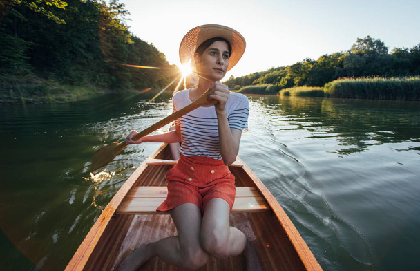 Pareja joven navegando en canoa en el atardecer del río  - Foto, Imagen