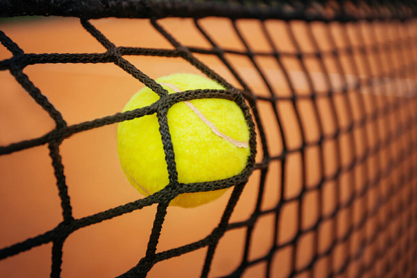 Tenisový míček naráží do tenisové sítě na tenisovém kurtu. Koncept selhání - Fotografie, Obrázek