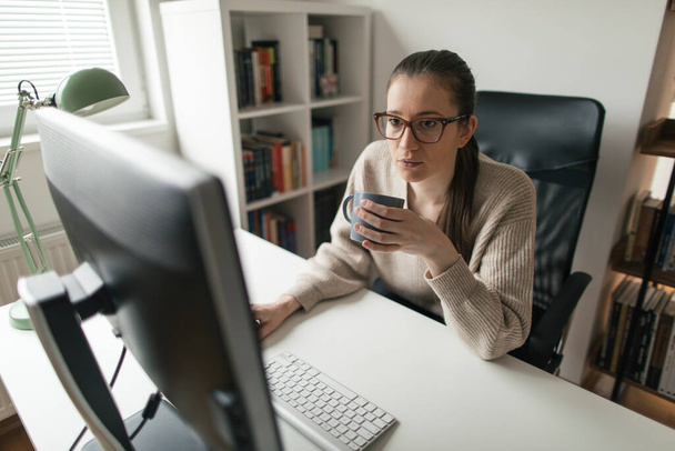 Жінка працює на настільному комп'ютері з її домашнього офісу. Бізнес-леді працюють довгі години з дому
 - Фото, зображення