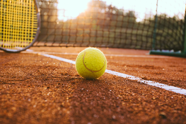 Теннисная ракетка и мяч на глиняной площадке - Фото, изображение