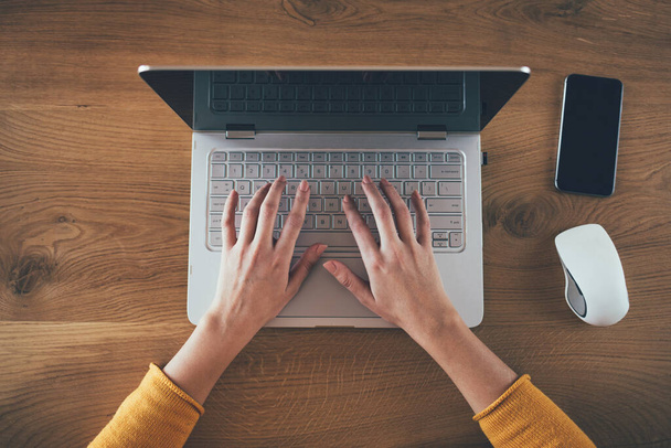 женщина работает с ноутбуком на деревянном столе - Фото, изображение