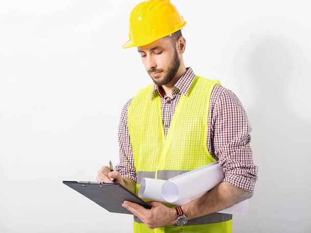 construction worker in yellow helmet and vest posing on white background - Foto, afbeelding