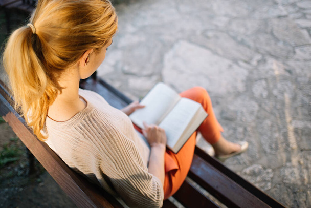 Donna seduta su una panchina e che legge un libro - Foto, immagini