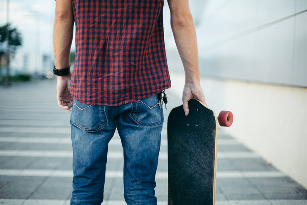 Midsection of skateboarder standing on street with skate - Fotografie, Obrázek