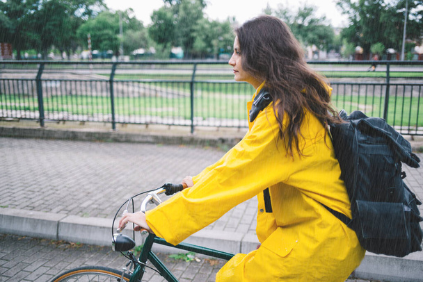 Sarı ceketli genç kız parkta bisiklet sürüyor. - Fotoğraf, Görsel