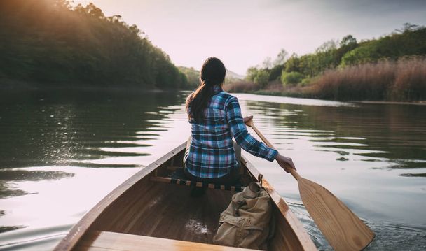 女の子カヌー。夕暮れ時にボートを漕ぐ旅行女性の背面図 - 写真・画像