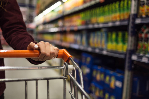Primer plano de la mano de la mujer empujando carrito de compras en el supermercado - Foto, imagen