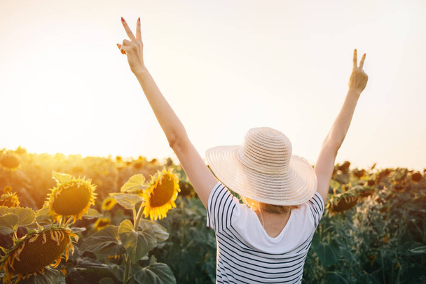 Хипстерская женщина в поле подсолнухов с поднятыми руками. Радость, успех, свобода, образ жизни - Фото, изображение