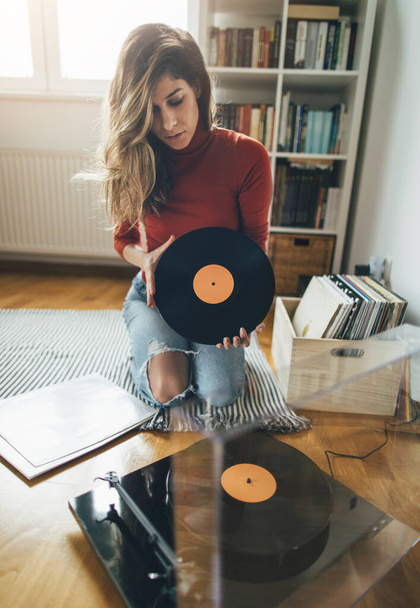 Hipster girl holding favourite vinyl record. Low angle view of girl enjoy music at home - Foto, Imagem