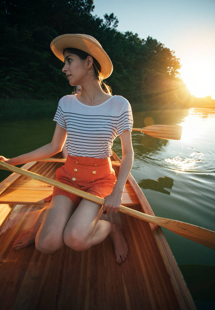 Handsome man and woman sailing on canoe on river sunset  - Photo, Image