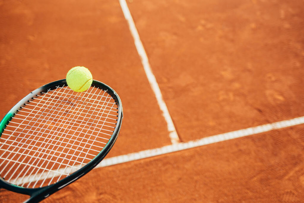 Lähikuva tennispallo ja maila savea kentällä - Valokuva, kuva