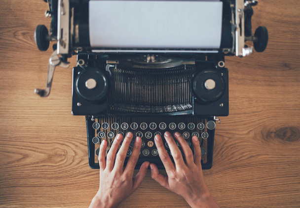 Ο συγγραφέας δακτυλογραφεί σε παλιά γραφομηχανή. Υψηλή γωνία άποψη των εκτυπώσεων γραμματέας σε vintage μηχανή δακτυλογράφησης - Φωτογραφία, εικόνα
