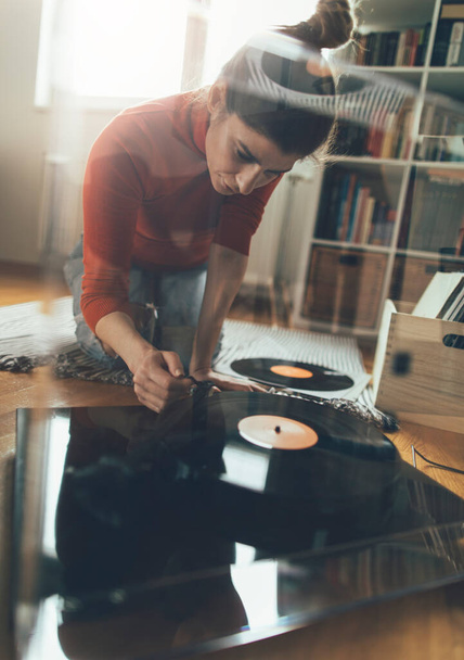 Young audiophile playing vinyl record on turntable from at her home. Enjoy vinyl records - Foto, Bild