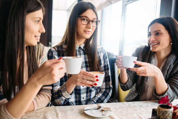 Houkuttelevia tyttöjä istuu kahvilassa ja juo kahvia - Valokuva, kuva