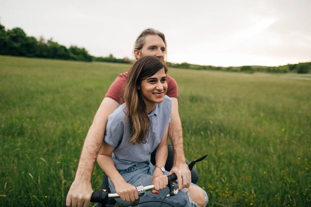 Beautiful couple ride a bike on the summer field  - Foto, afbeelding