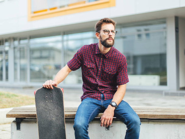 Homem barbudo sentado no banco com patins  - Foto, Imagem