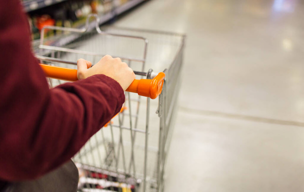 Close up of woman hand pushing shopping cart in supermarket - Foto, afbeelding