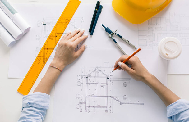 Женщина-архитектор рисует план, дизайн, геометрические формы карандашом на большом листе бумаги за рабочим столом. - Фото, изображение