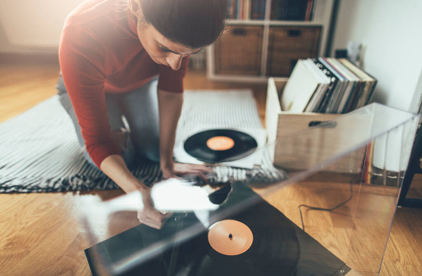 Young audiophile playing vinyl record on turntable from at her home. Enjoy vinyl records - Photo, Image