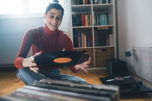 Hipster girl holding favourite vinyl record. Low angle view of girl enjoy music at home - Valokuva, kuva