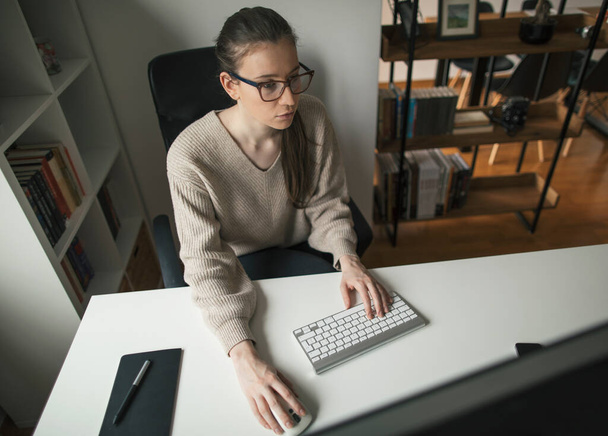 Γυναίκα που δουλεύει σε επιτραπέζιο υπολογιστή από το γραφείο της στο σπίτι. Επιχειρηματίας που εργάζεται πολλές ώρες από το σπίτι - Φωτογραφία, εικόνα