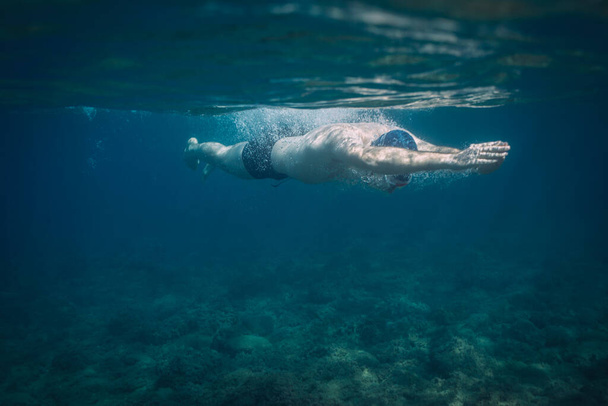 Человек плавает глубоко под водой  - Фото, изображение