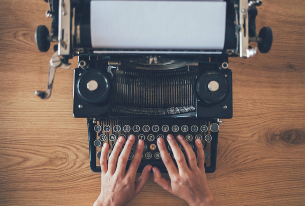 Schriftsteller tippt auf alter Schreibmaschine. Hochwinkelansicht von Sekretärabzügen auf alten Schreibmaschinen - Foto, Bild