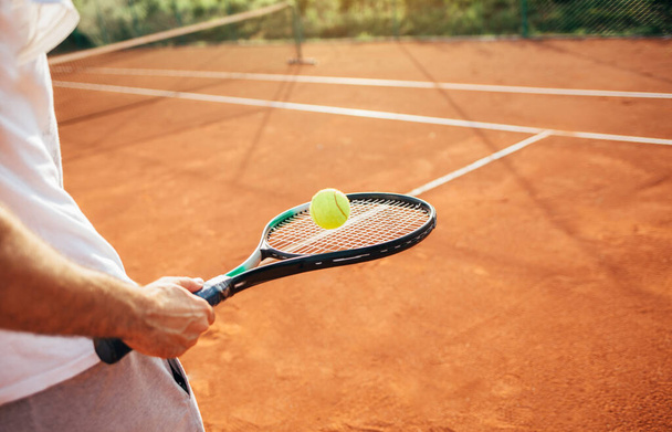 Gros plan du joueur de tennis tenant raquette et balle. Joueur de tennis sur terrain d'argile  - Photo, image