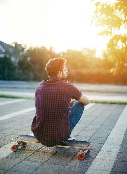 achteraanzicht van de mens zittend op skateboard - Foto, afbeelding