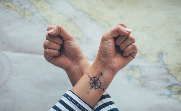 Σταυρωτές γροθιές με τατουάζ πυξίδα στον ένα αστράγαλο. Ταξιδιωτική έννοια - Φωτογραφία, εικόνα