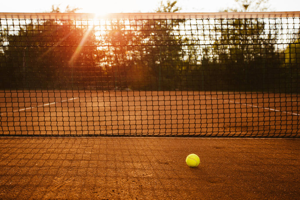 Court de tennis au coucher du soleil avec silhouette de joueur en arrière-plan - Photo, image
