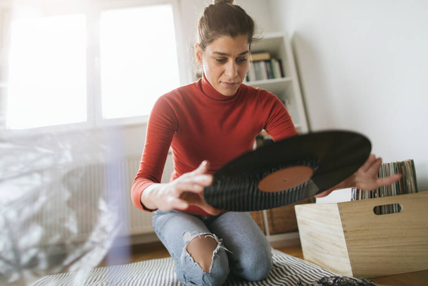 Hipster girl holding favourite vinyl record. Low angle view of girl enjoy music at home - Foto, afbeelding