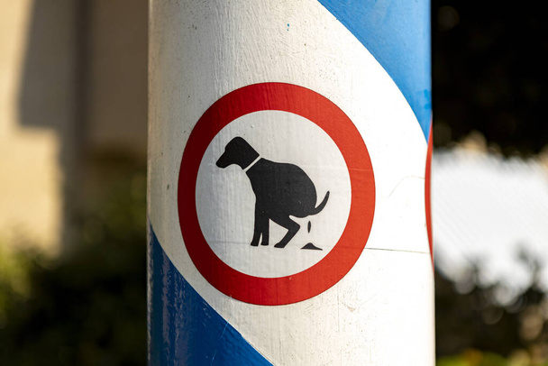 NIJVERDAL, NETHERLANDS - Aug 15, 2020: Dutch sign with red band and icon image of a dog pooping meaning this is not a dog toilet area - Foto, Imagen