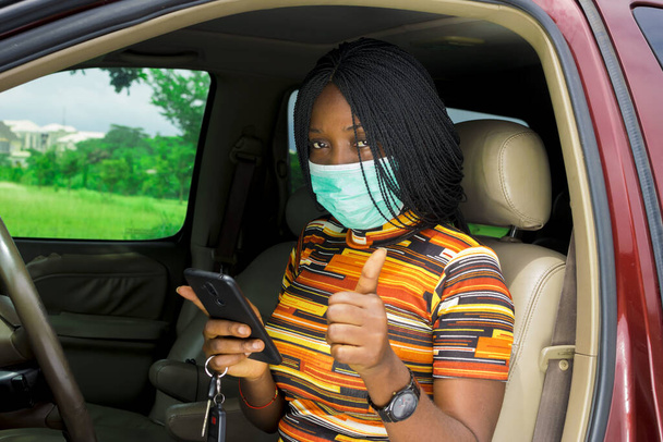 A young African-American female wearing a medical mask using her smartphone - Fotoğraf, Görsel