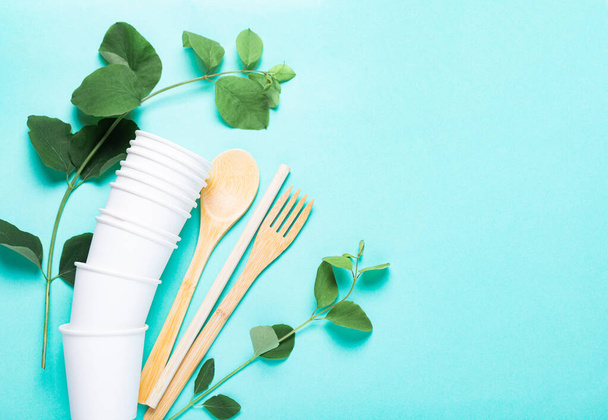 Eco dishes. Paper cups, wooden fork, spoon, knife, tube, on a blue background. The concept of recycling, ecology, planet conservation, zero waste - Photo, Image