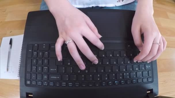 Cierre en persona escribiendo en su computadora portátil mientras se sientan en un piso de madera - Imágenes, Vídeo